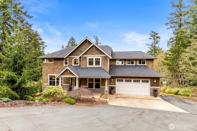 view of front of house with an attached garage, stone siding, and aphalt driveway