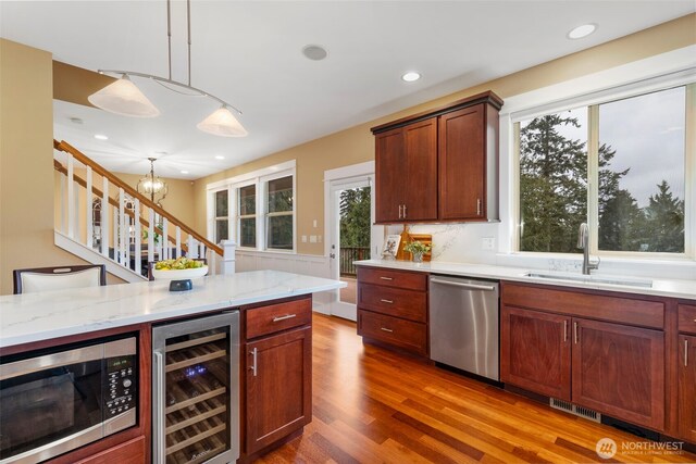kitchen with wine cooler, a sink, wood finished floors, stainless steel appliances, and visible vents