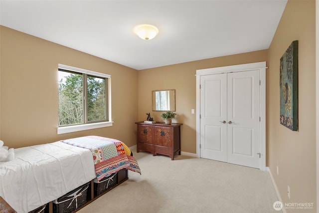 bedroom with baseboards, a closet, and light carpet