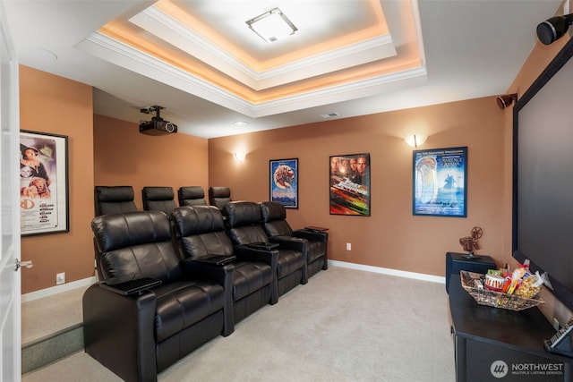 home theater featuring light colored carpet, ornamental molding, baseboards, and a raised ceiling