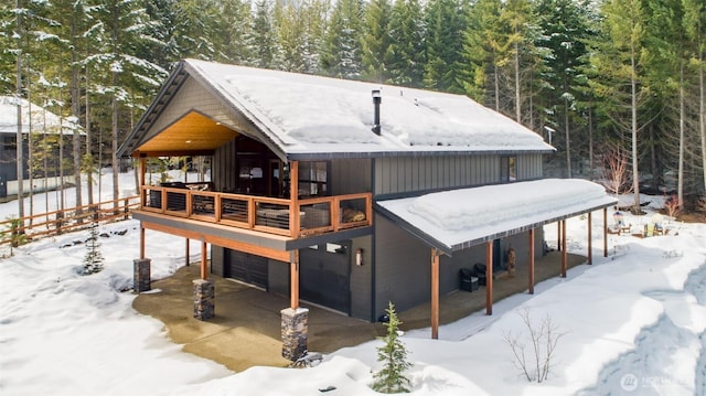 snow covered house featuring a garage