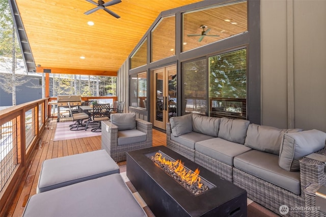 sunroom featuring french doors, an outdoor living space with a fire pit, ceiling fan, and wood ceiling