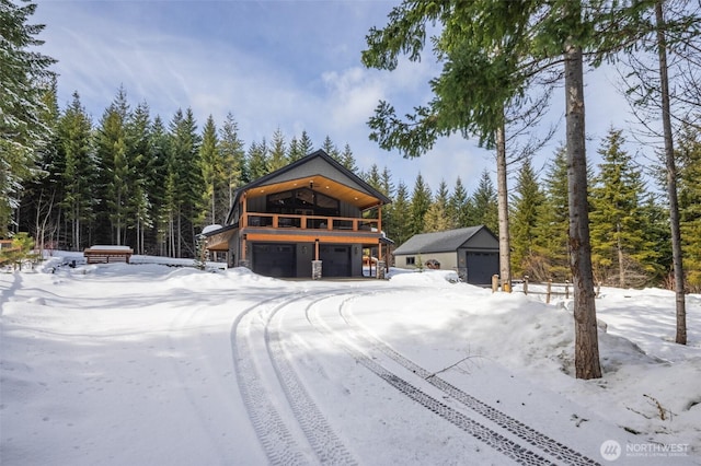 view of front of property featuring a detached garage, a view of trees, and an outdoor structure
