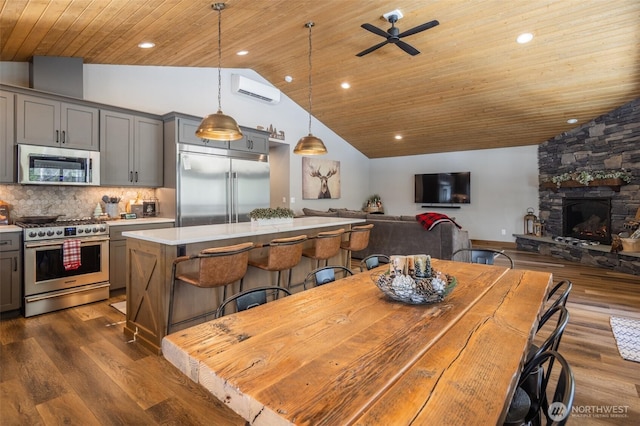 dining space with ceiling fan, lofted ceiling, dark wood-type flooring, a wall mounted AC, and wood ceiling