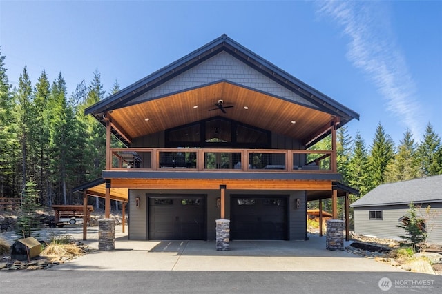 view of front of house featuring ceiling fan, a balcony, board and batten siding, an attached garage, and driveway
