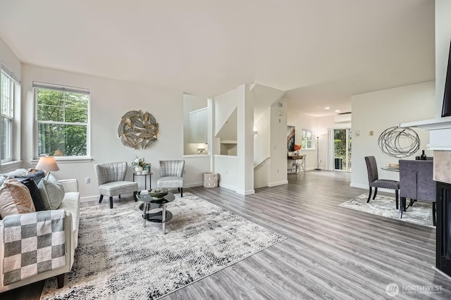 living area with plenty of natural light, baseboards, wood finished floors, and stairway