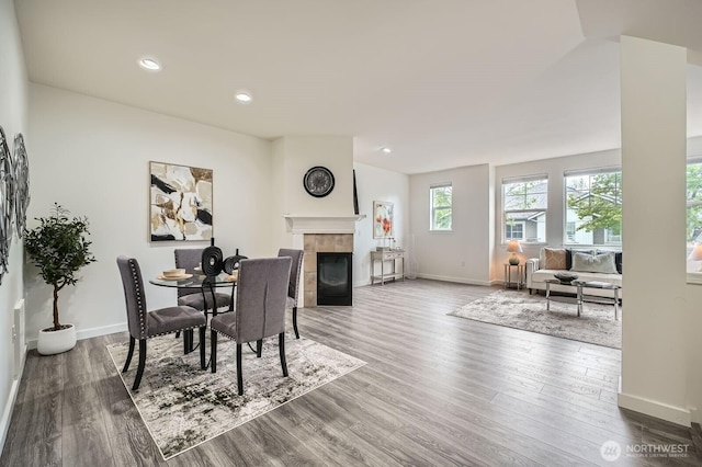 dining room with recessed lighting, baseboards, wood finished floors, and a tile fireplace