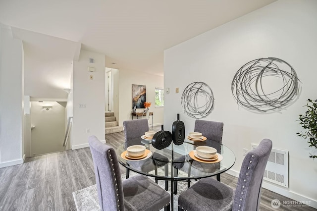 dining area with baseboards, wood finished floors, and stairway