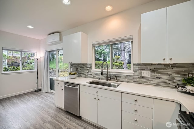 kitchen with stainless steel dishwasher, a sink, white cabinetry, and light countertops