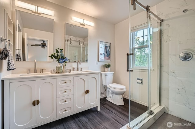 bathroom with a sink, wood finished floors, toilet, and a shower stall