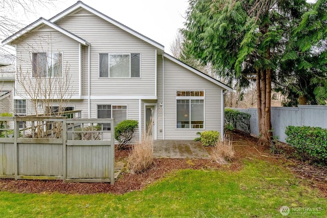 rear view of house with a yard and fence