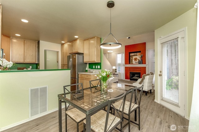 dining space featuring recessed lighting, a fireplace, visible vents, and light wood-type flooring