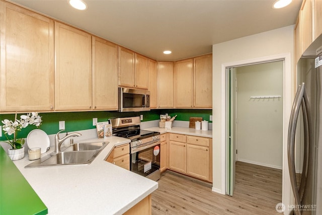 kitchen with recessed lighting, light countertops, appliances with stainless steel finishes, a sink, and light brown cabinetry