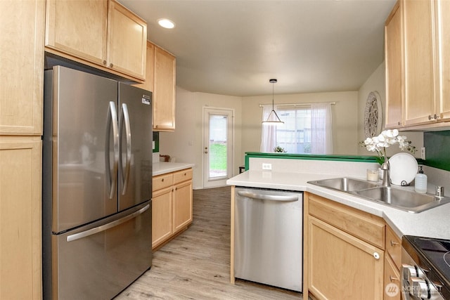 kitchen with a peninsula, light brown cabinets, a sink, and appliances with stainless steel finishes