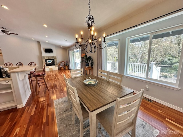 dining area with vaulted ceiling, wood-type flooring, baseboards, visible vents, and a multi sided fireplace