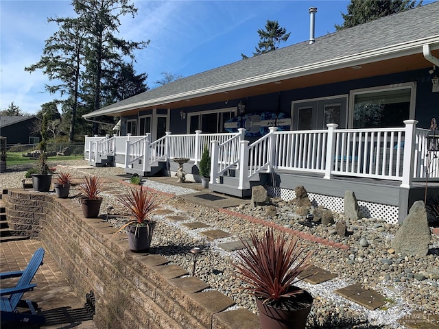 exterior space with a porch and a shingled roof