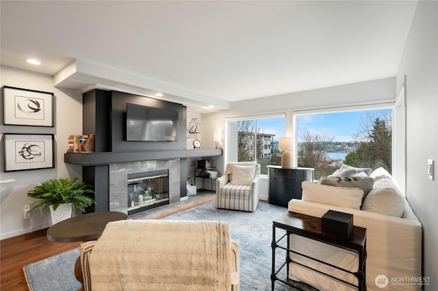living area featuring recessed lighting, wood finished floors, baseboards, and a high end fireplace