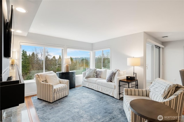 living room with a wealth of natural light, visible vents, wood finished floors, and recessed lighting