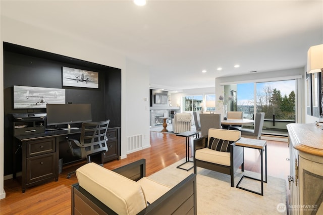 living area with light wood-type flooring, visible vents, recessed lighting, a fireplace, and baseboards