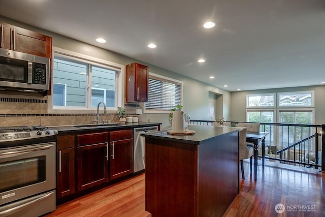 2120 W Ruffner St, Seattle, WA 98199 - kitchen with light wood-type flooring, dark countertops, a sink, and appliances with stainless steel finishes