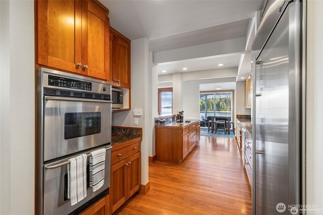 17884 S Angeline Ave NE, Suquamish, WA 98392 - kitchen featuring stainless steel appliances, brown cabinetry, light wood-style flooring, recessed lighting, and dark countertops