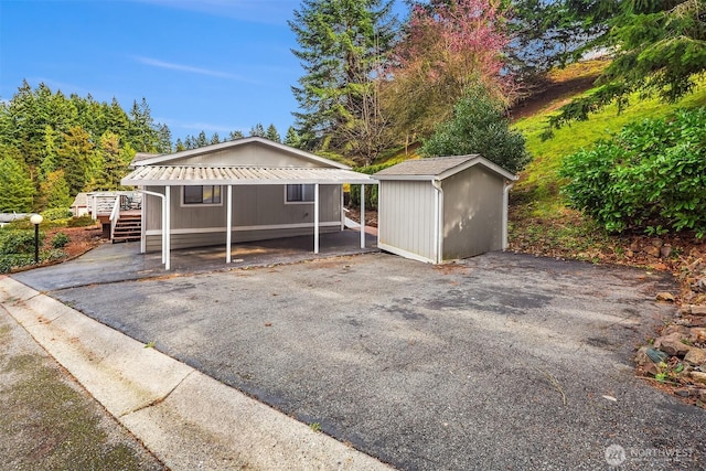 view of front of property featuring driveway, a shed, stairway, a detached carport, and an outdoor structure