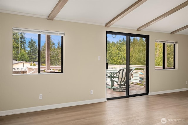 unfurnished room featuring baseboards, beam ceiling, and wood finished floors