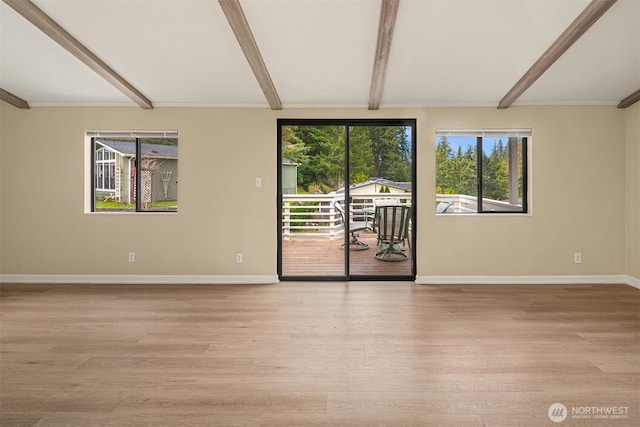 spare room featuring beam ceiling, baseboards, and light wood-style floors