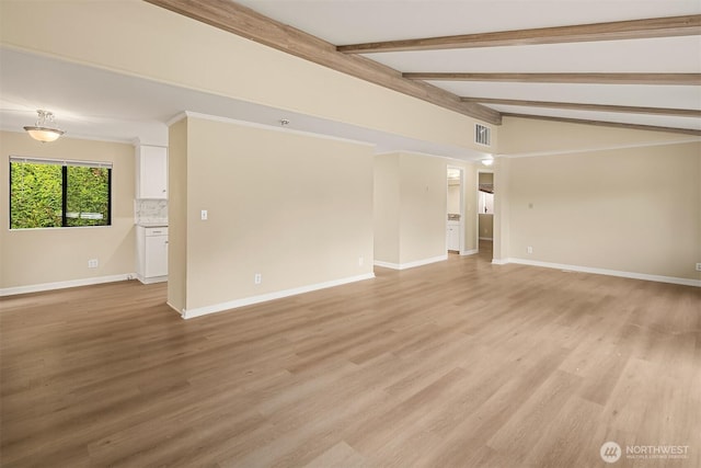 spare room featuring light wood finished floors, visible vents, vaulted ceiling with beams, and baseboards