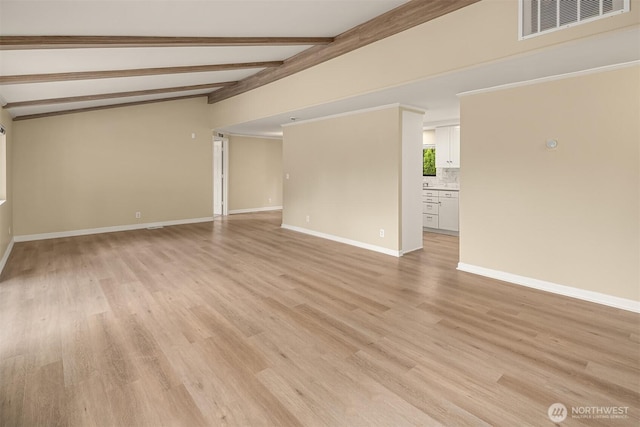 empty room with visible vents, baseboards, lofted ceiling with beams, and light wood-style floors