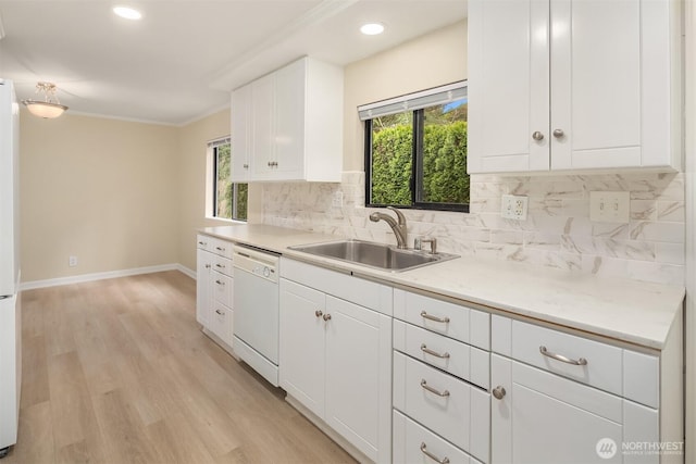 kitchen featuring tasteful backsplash, light wood-type flooring, a wealth of natural light, white dishwasher, and a sink