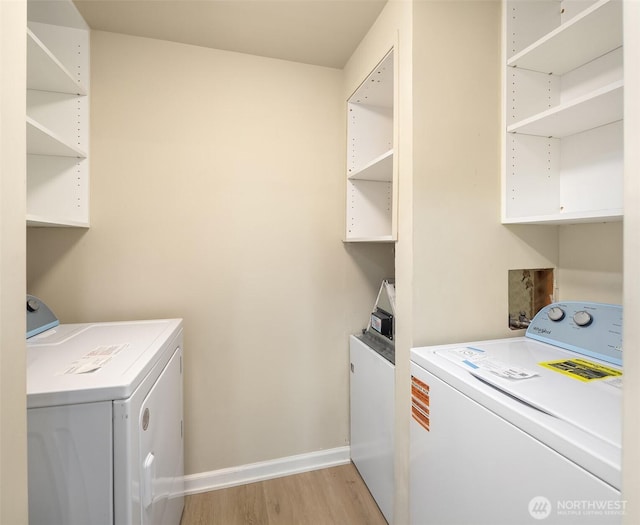 washroom with laundry area, washing machine and dryer, light wood-style floors, and baseboards