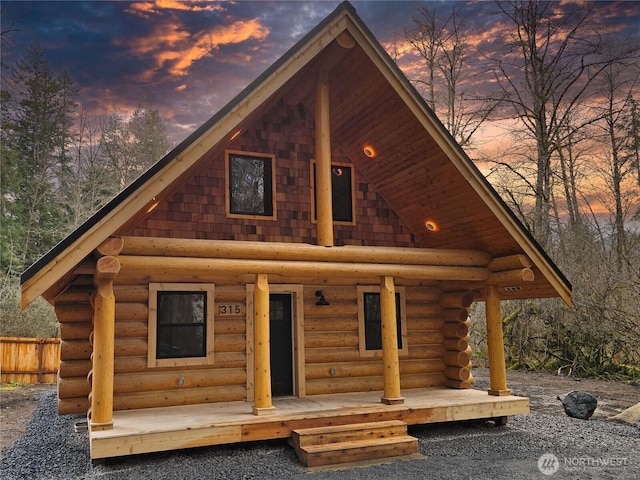 315 Skate Creek Rd N, Ashford, WA 98304 - back of property at dusk with log siding, fence, and covered porch