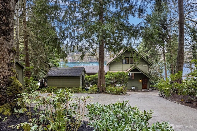 view of front facade featuring driveway, an outdoor structure, and a storage shed