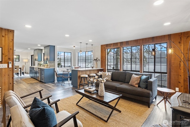 living area with light wood-style flooring, wood walls, and recessed lighting