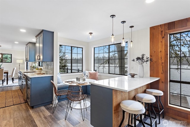 kitchen featuring a wealth of natural light, light countertops, wood finished floors, and a breakfast bar