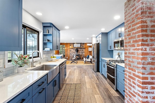 kitchen featuring tasteful backsplash, a wood stove, a sink, light wood-style floors, and appliances with stainless steel finishes