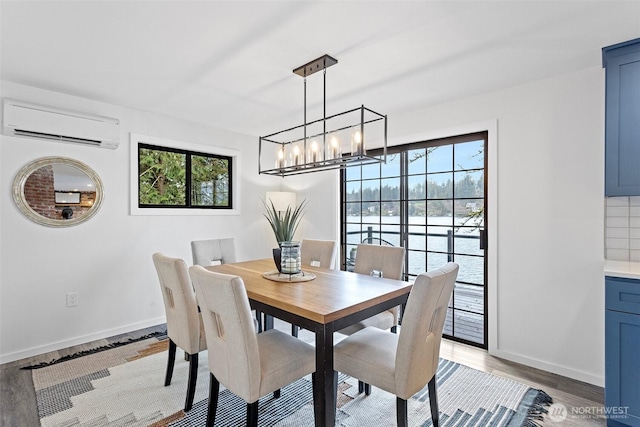 dining space featuring a wealth of natural light, an AC wall unit, a notable chandelier, and light wood finished floors