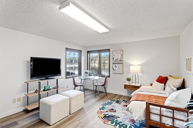 living area with baseboards, wood finished floors, and a textured ceiling