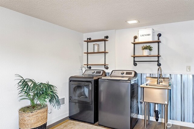 laundry room with washer and clothes dryer, baseboards, a textured ceiling, laundry area, and wood finished floors
