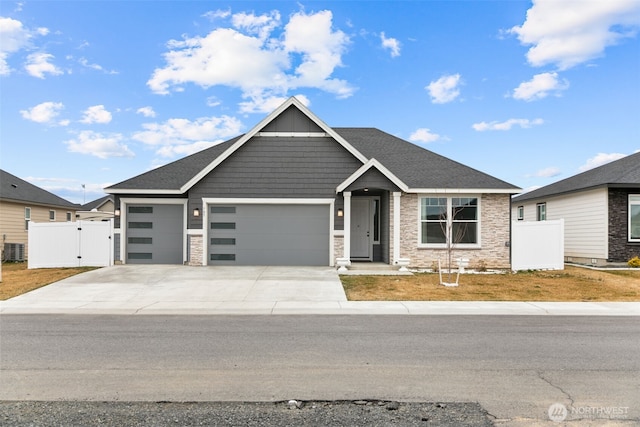 view of front of house featuring a gate, a garage, stone siding, and driveway