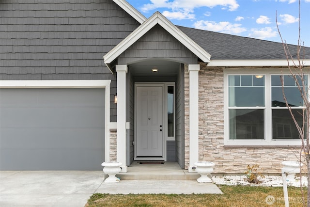doorway to property featuring stone siding, roof with shingles, and concrete driveway