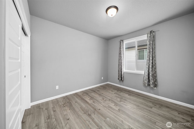 unfurnished bedroom featuring wood finished floors, baseboards, and a textured ceiling
