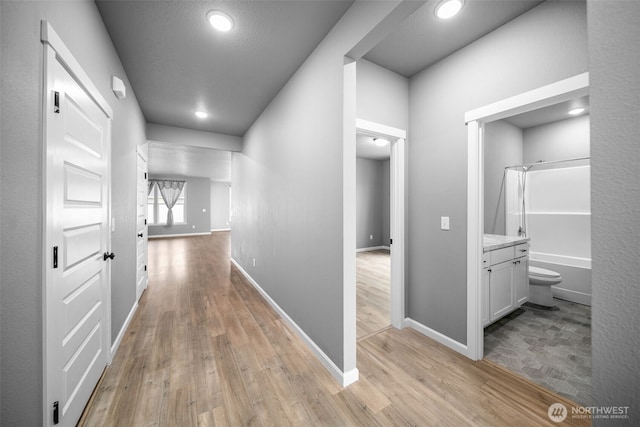 corridor with baseboards and light wood-style floors