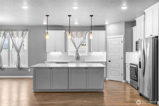 kitchen with a sink, stainless steel appliances, a center island, and light countertops