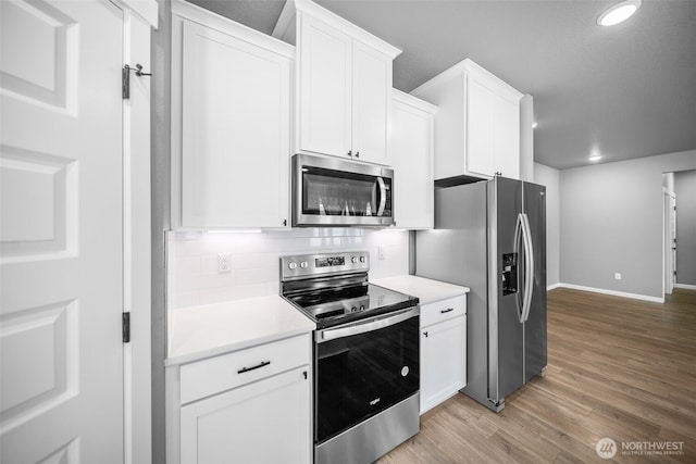 kitchen featuring tasteful backsplash, light countertops, light wood-style flooring, white cabinets, and stainless steel appliances