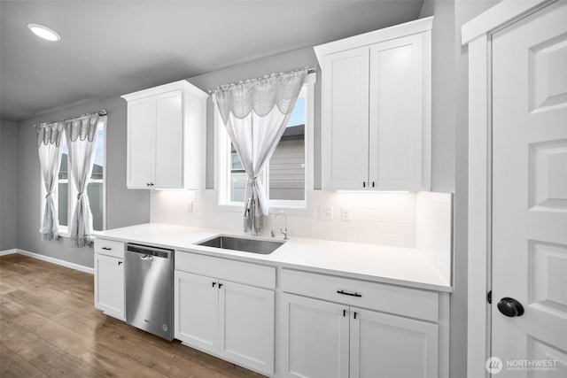 kitchen featuring a healthy amount of sunlight, a sink, decorative backsplash, white cabinets, and stainless steel dishwasher