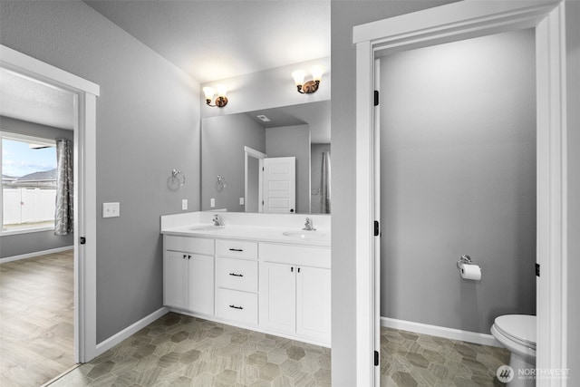 full bathroom with a sink, baseboards, and double vanity