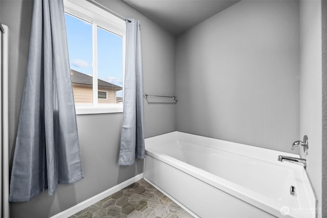 bathroom featuring a bath and baseboards