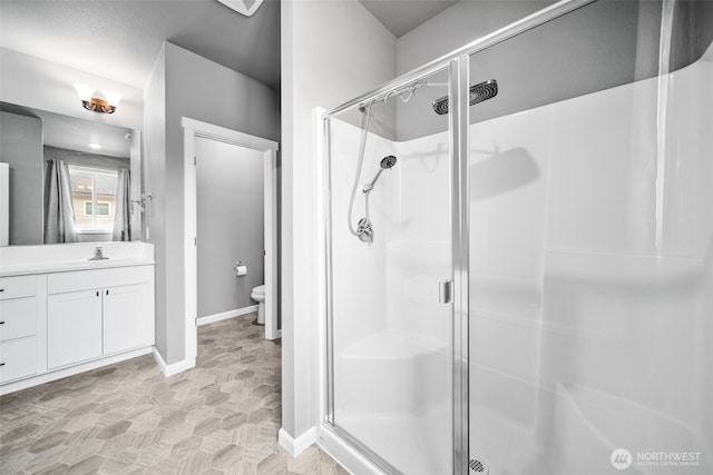 full bathroom with baseboards, vanity, toilet, and a shower stall